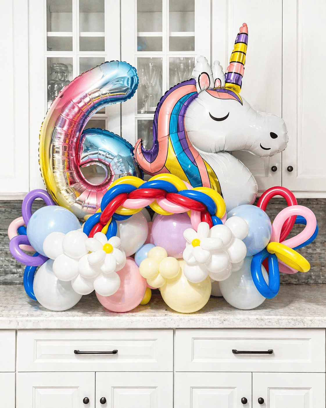Unicorn themed sixth birthday balloon display with a large number six